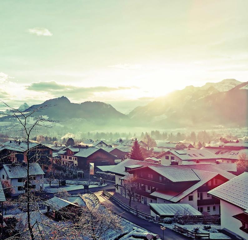 a village with snow covered roofs and mountains in the background at Sunrise Pfronten - Budget in Pfronten