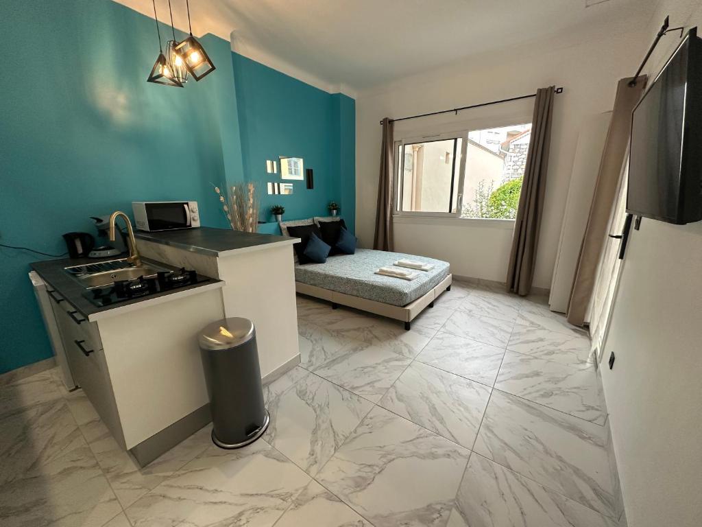 a kitchen with a stove and a couch in a room at La maison de Julia menton studio bleuté in Menton