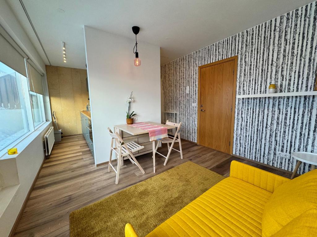 een woonkamer met een gele bank en een tafel bij Bright & Cozy Central Studio in Reykjavík