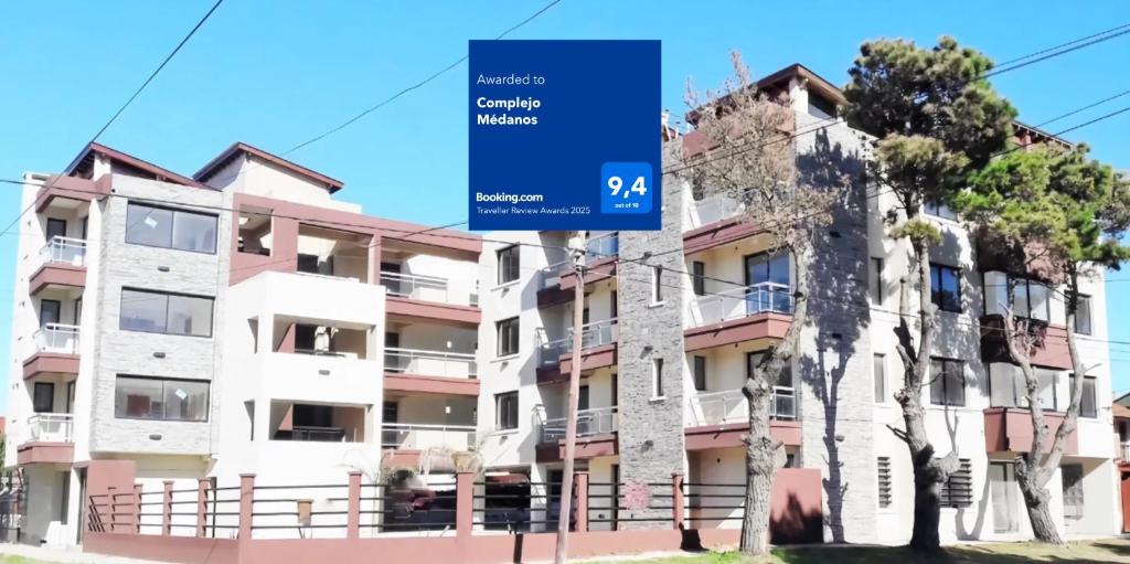 an apartment building with a blue sign in front of it at Complejo Médanos in San Bernardo