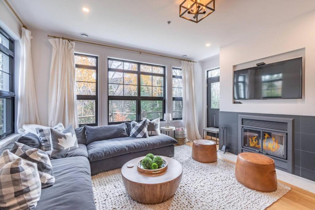 a living room with a couch and a fire place at Unwind in Style Les Eaux 215-6 in Mont-Tremblant