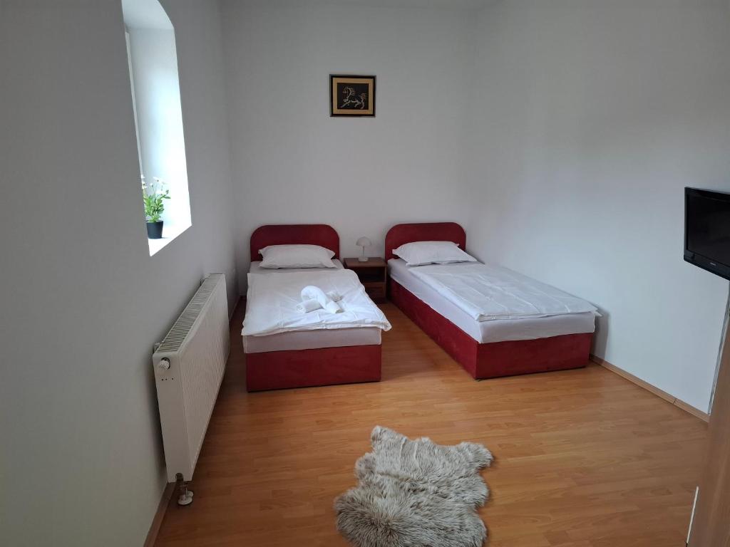 two beds in a small room with a rug at Krčma i prenočište Fra Luka Požega in Požega
