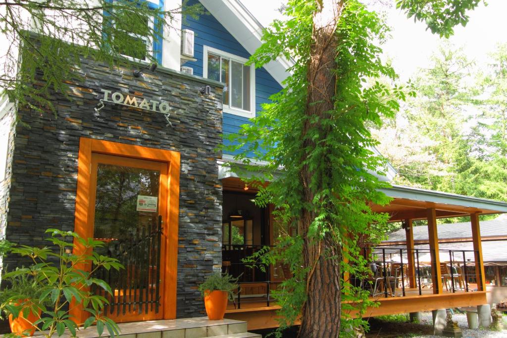 白馬村にある白馬 姫川温泉 ペンション TOMATOの石造りの外観と玄関付きの家