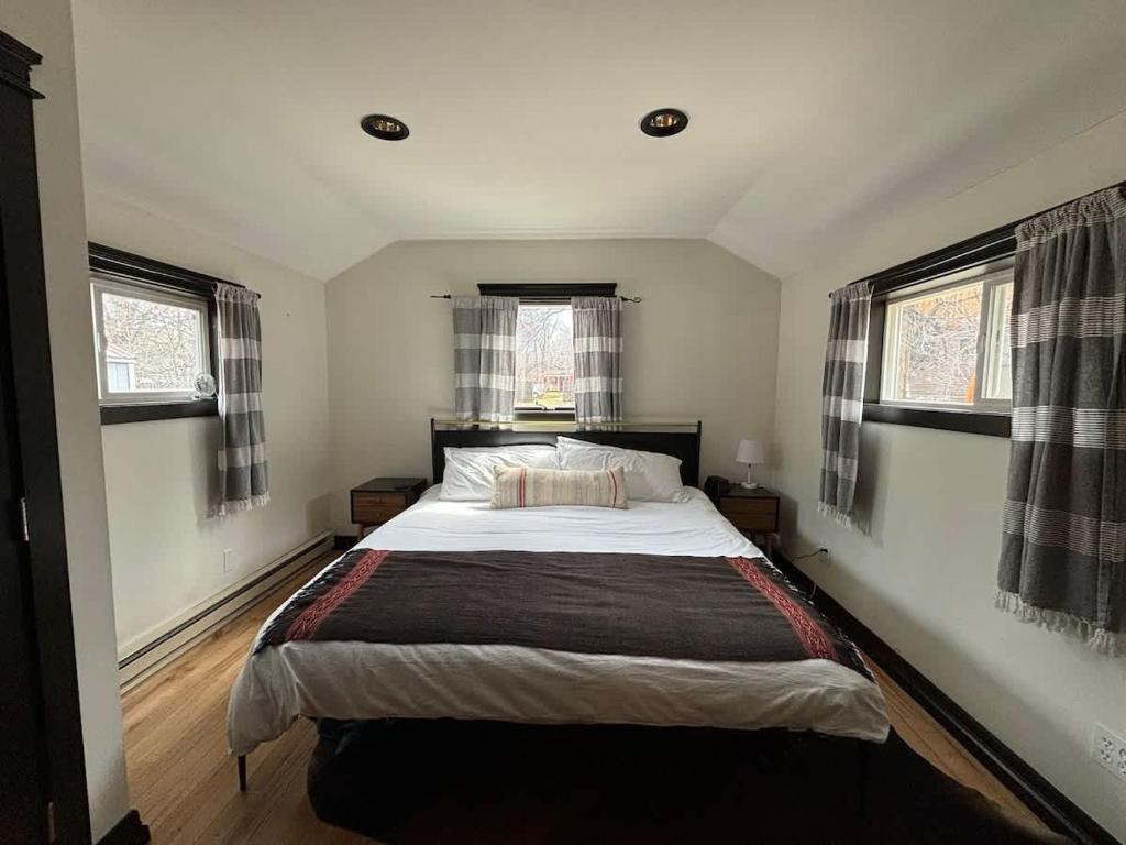 a bedroom with a large bed and two windows at The Purple Palace - Historic Downtown BZN in Bozeman