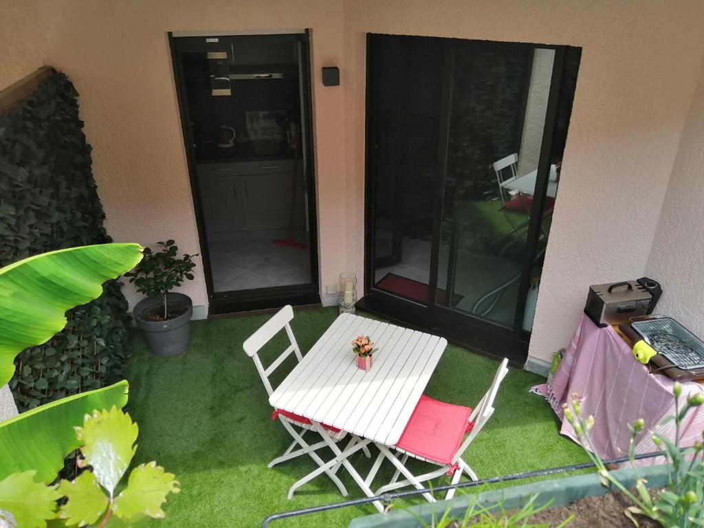 une table et des chaises blanches sur une cour avec de l'herbe dans l'établissement Studio a 3min a pied des plages et proche de Cannes, à Mandelieu-la-Napoule