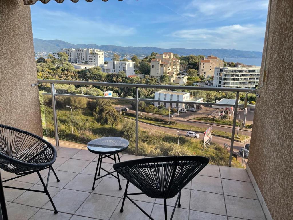ein Balkon mit Stühlen und Blick auf die Stadt in der Unterkunft Appartement vue sur le golfe d ajaccio in Ajaccio