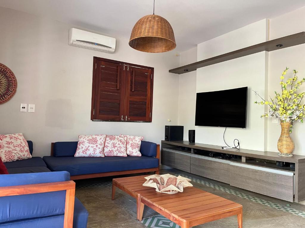 Una sala de estar con un sofá azul y un televisor en Bangalôs da Barra Chalé 2, en Barra Grande