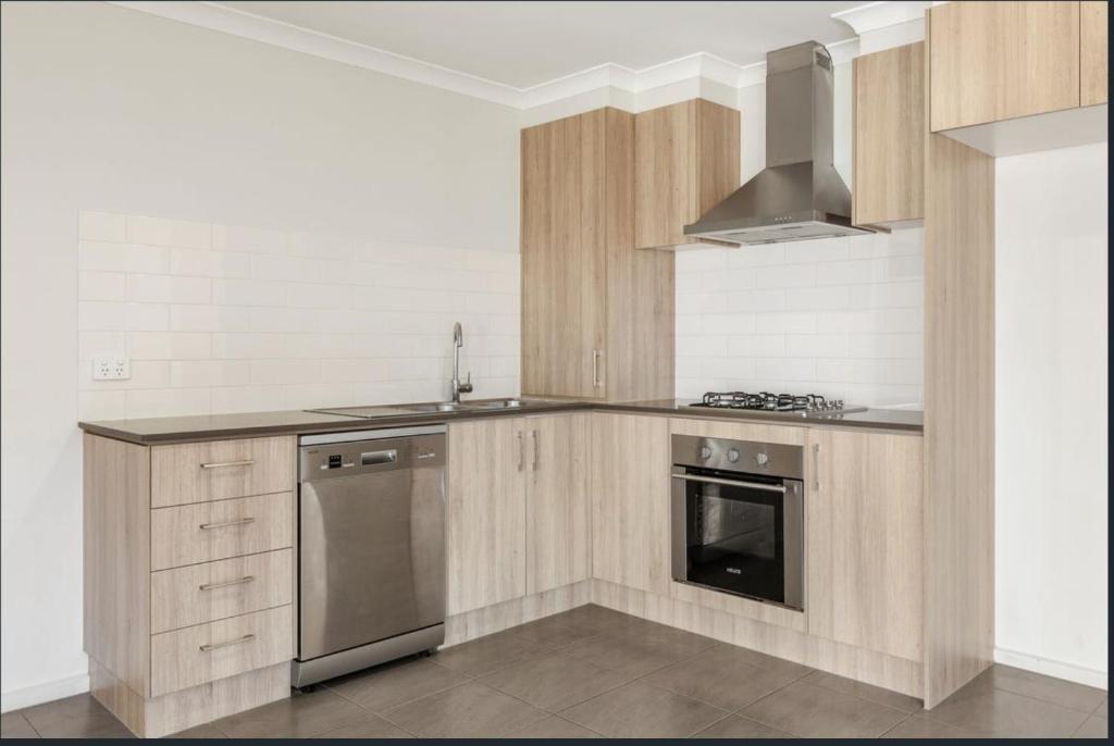 a kitchen with wooden cabinets and a stainless steel appliance at stay live love in Epping