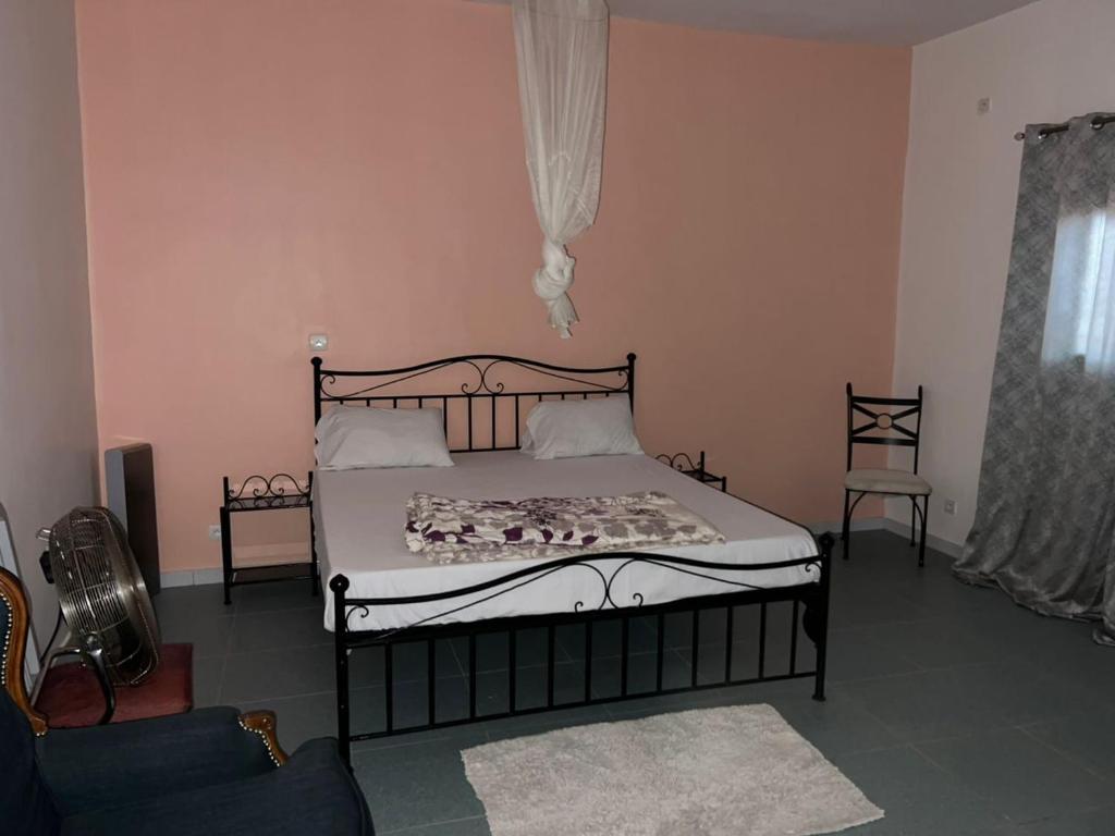 a bedroom with a bed and a couch and a window at Gite de la savane in Sindia