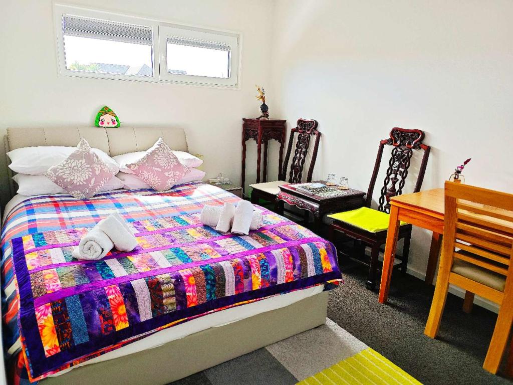 基督城LilyのHome Elegant Retreat near Riccarton Mall的一间卧室，配有一张床、一张桌子和几把椅子