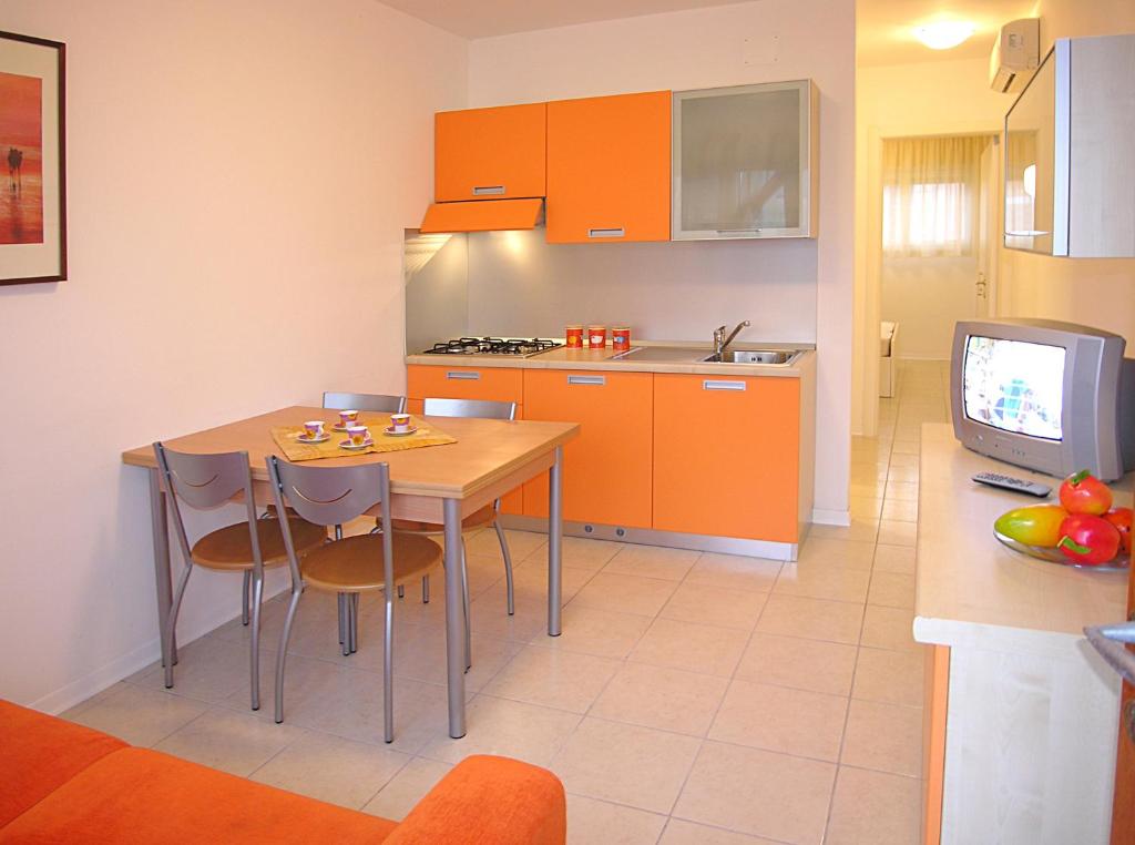 a kitchen with a table and a kitchen with orange cabinets at Appartamenti Ai Pini in Bibione