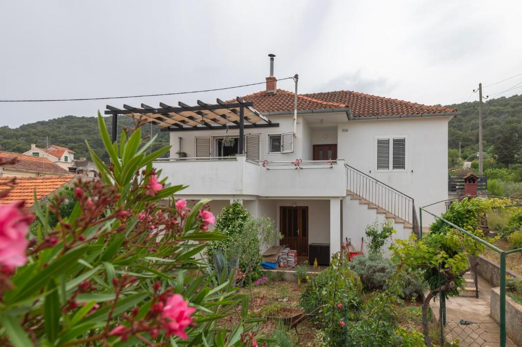 ein weißes Haus mit einem Balkon in einem Garten in der Unterkunft Apartment Marinsko in Veli Iž