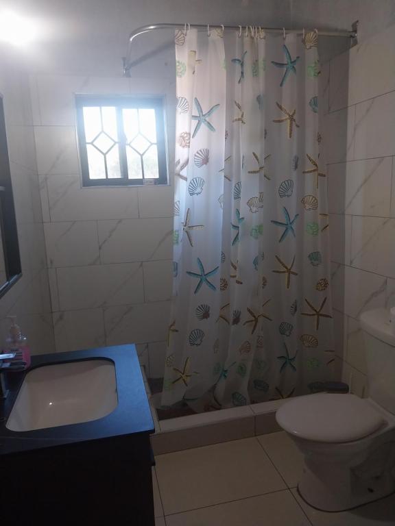 a bathroom with a toilet and a shower curtain at Jamaica Beach in Tower Isle