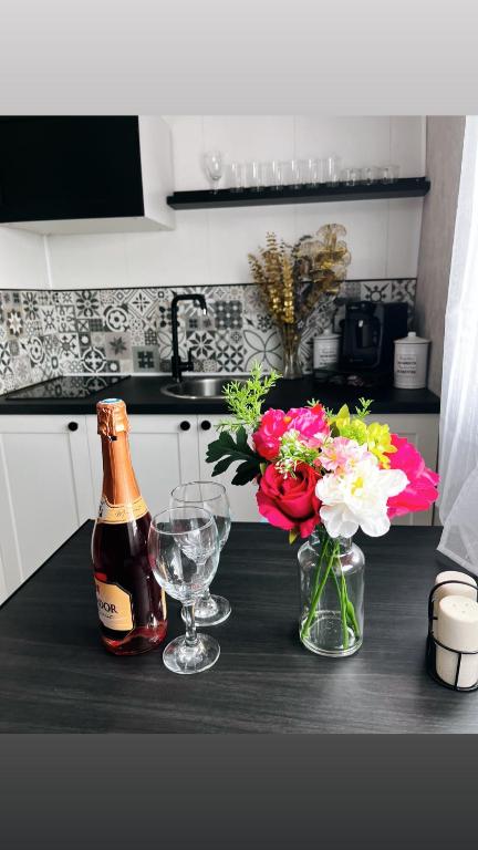 - une bouteille de bière, 2 verres et des fleurs sur un comptoir dans l'établissement Studio coup de cœur, à Forbach