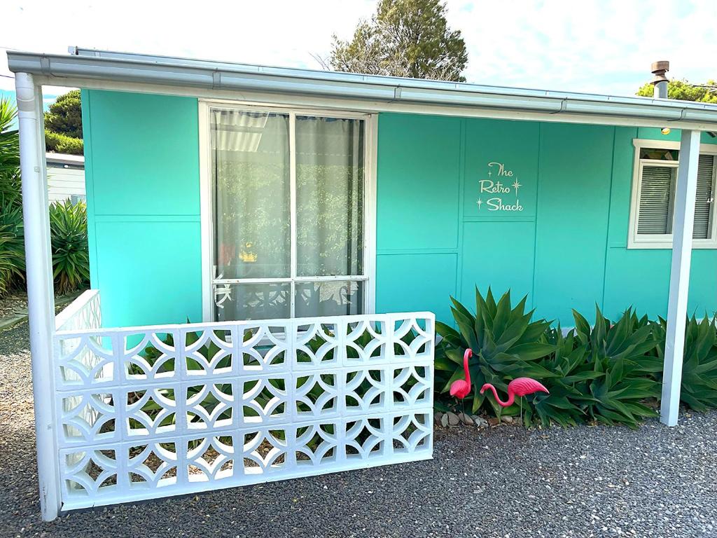 una casa azul con una valla blanca delante de ella en The ReTrO Beach Shack, en Aldinga Beach