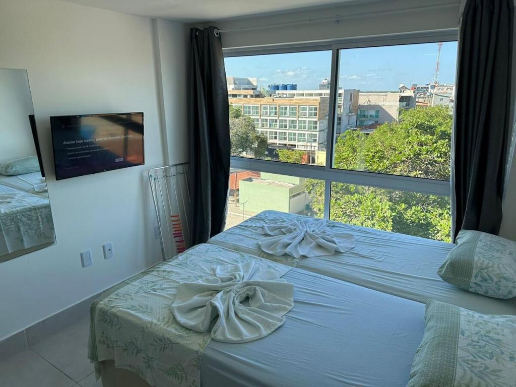 ein Bett in einem Schlafzimmer mit einem großen Fenster in der Unterkunft Apartamento em Porto de Galinhas in Porto De Galinhas