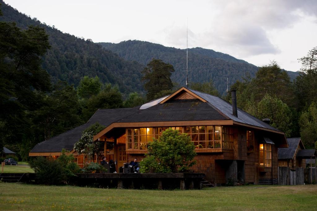 a large wooden house in the middle of a field at El Pangue Lodge in Puerto Puyuhuapi