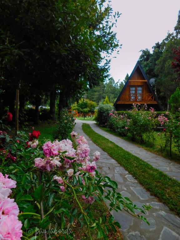 a garden with flowers and a house in the background at Cabañas Mijos in El Bolsón
