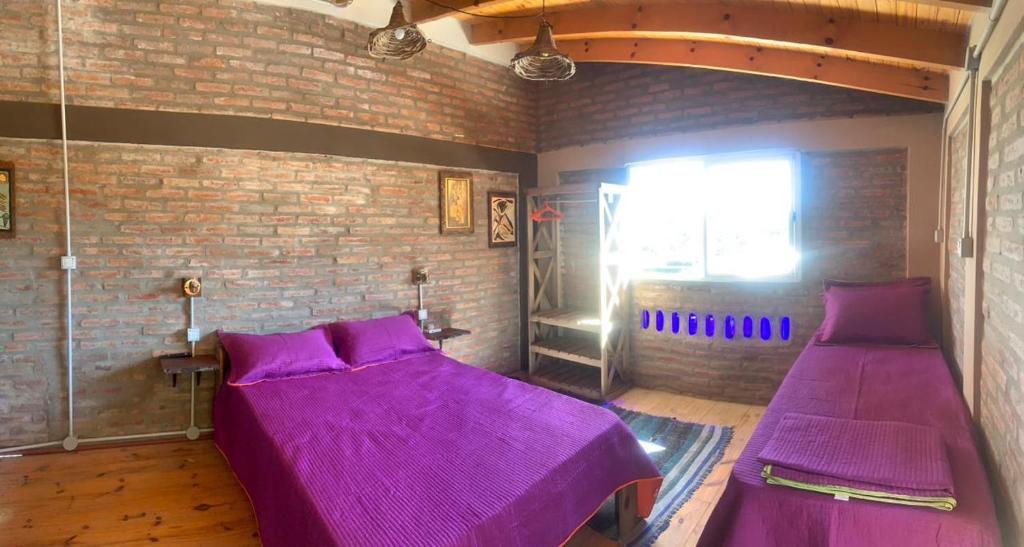 圣罗莎卡拉穆奇塔县Bauha Mini Apart的砖墙间内的两张紫色床