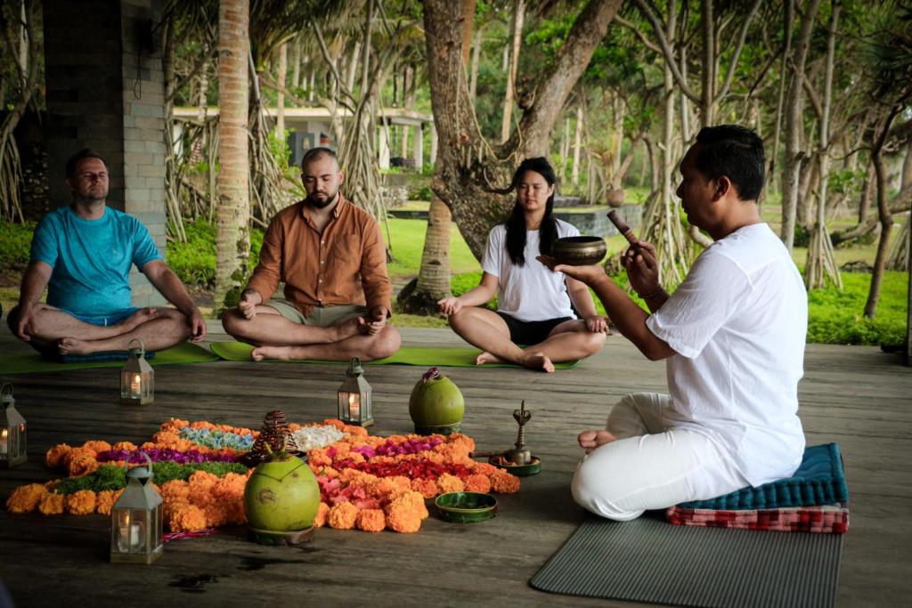 a group of people sitting on the ground with food at Kelapa Retreat & Spa in Pulukan