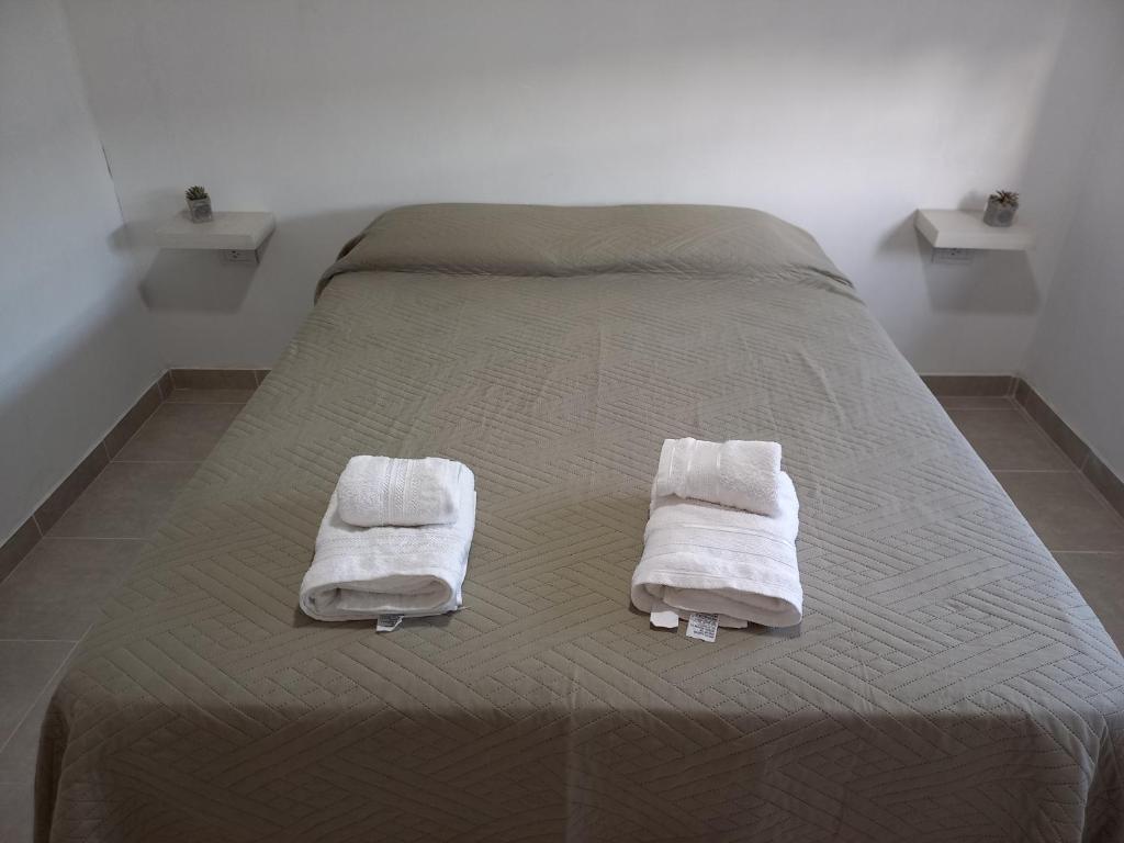 Una cama con dos toallas blancas encima. en Departamentos TUNQUELEN, en Río Colorado