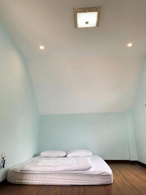 ein Bett in einem Zimmer mit einer weißen Wand in der Unterkunft NHỚ House IV in Da Lat