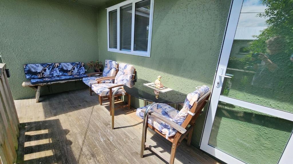 a patio with chairs and a table on a porch at Guest Suite with private entry own kitchen and bathroom in Oamaru