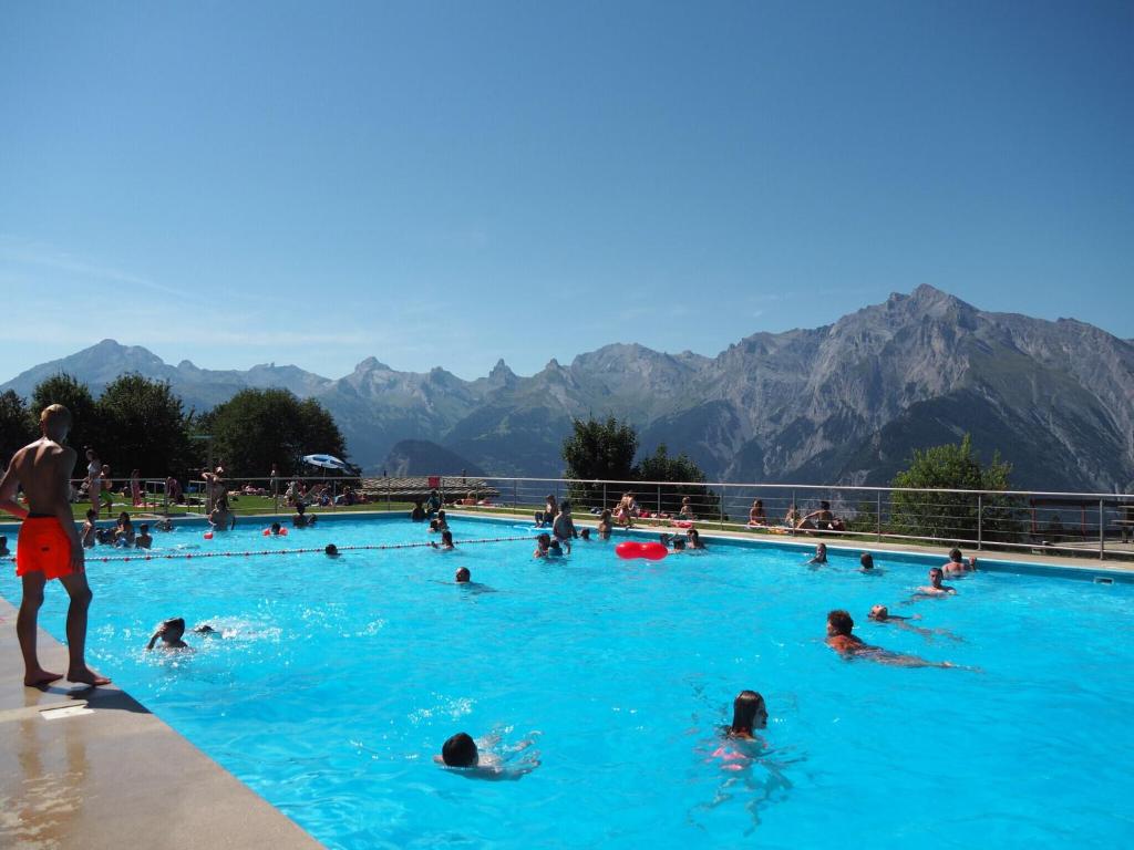 a group of people swimming in a swimming pool at Spacious apartment in Nendaz in Nendaz