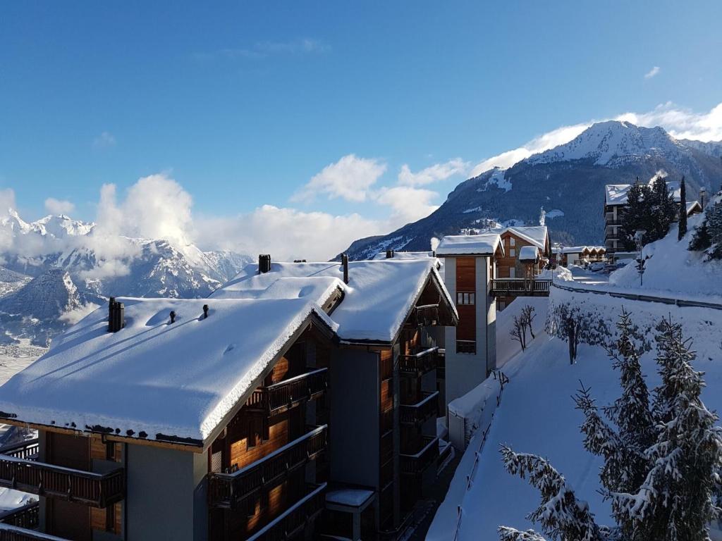 a building covered in snow with mountains in the background at Family apartment with terrace in Veysonnaz