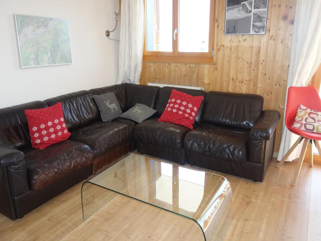 a brown leather couch with red and grey pillows at Cozy apartment for groups in Veysonnaz