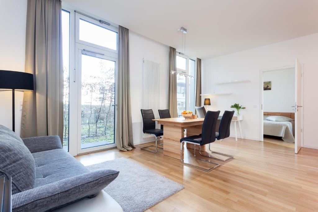 - un salon avec un canapé et une table avec des chaises dans l'établissement Modern Apartment in the Luxury Complex Marthashof, à Berlin