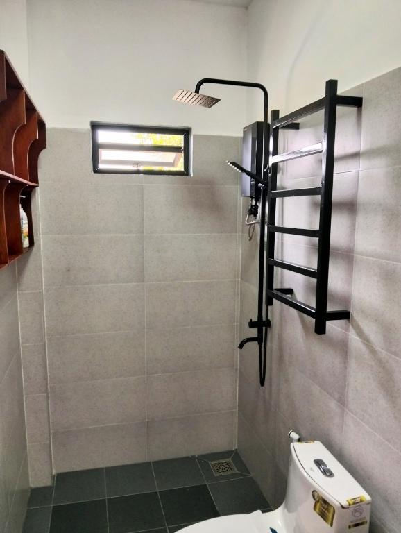 a bathroom with a toilet and a glass shower at Baksaei Retreat Ricefield Villas in Kampot