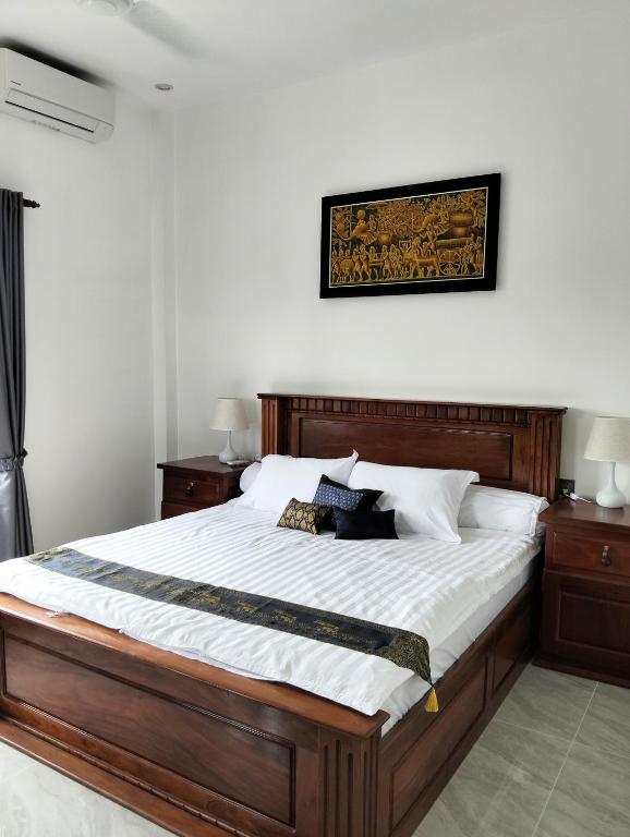 a bedroom with a large wooden bed with white sheets at Baksaei Retreat Ricefield Villas in Kampot