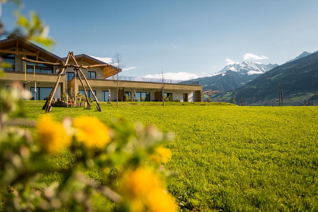 ein Haus auf einem Feld mit Bergen im Hintergrund in der Unterkunft Pataunerhof Betulla Quercus in Dorf Tirol