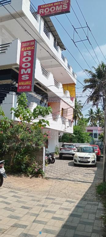 a building with cars parked in front of it at Tabish INN in Trivandrum