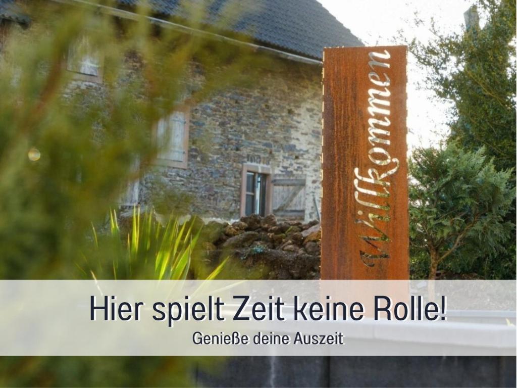 a wooden sign in front of a house at Ferienwohnung Alte Schule Kennfus - Ruhe genießen in Bad Bertrich