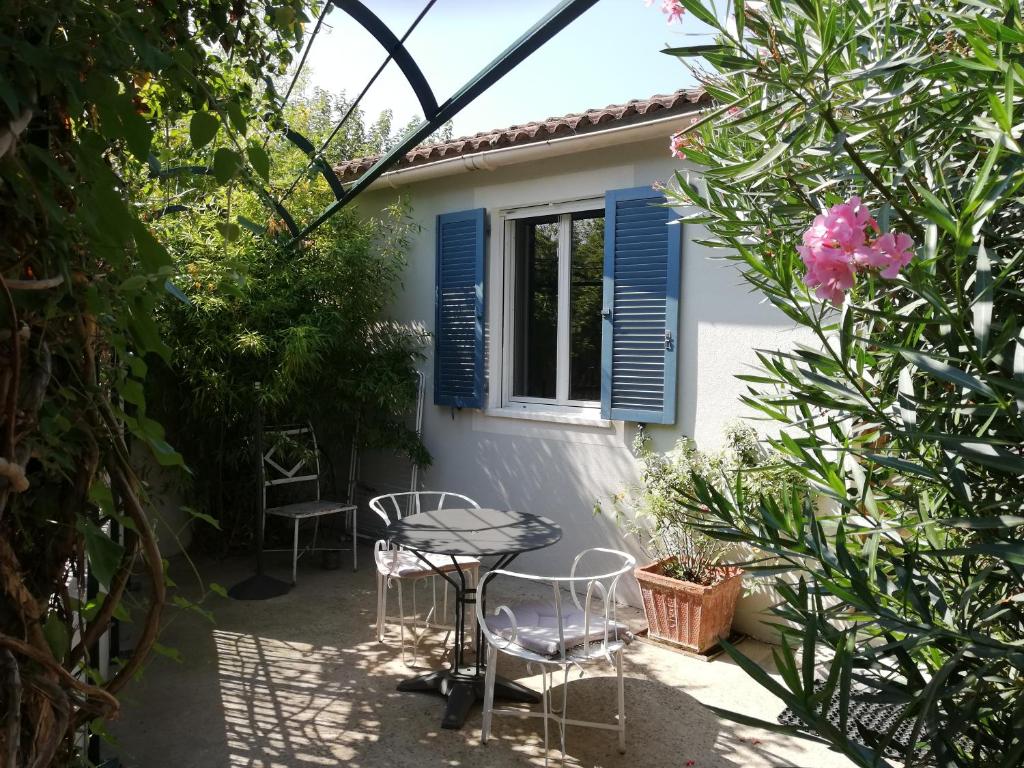 un patio avec une table et des chaises devant une maison dans l'établissement Gîte de la treille, à LʼIsle-sur-la-Sorgue