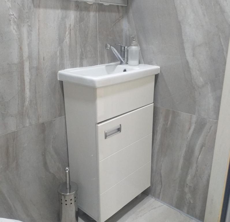 a bathroom with a white sink and a wall at Apartman Marina Aranđelovac in Arandjelovac