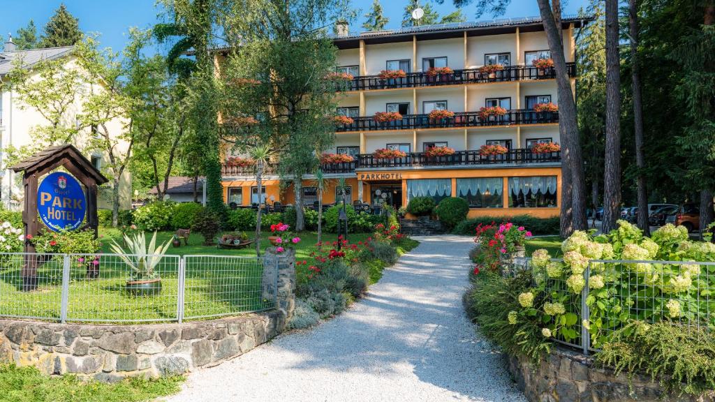 ein Hotel mit einem Garten vor einem Gebäude in der Unterkunft Parkhotel Zuzek in Sankt Kanzian am Klopeiner See