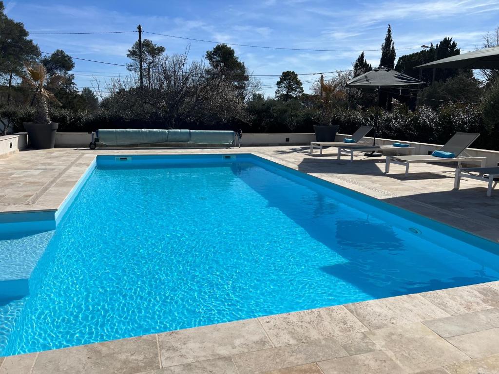 une piscine avec de l'eau bleue dans une cour dans l'établissement Villa Rougiers - Maison climatisée avec piscine, à Saint-Maximin-la-Sainte-Baume