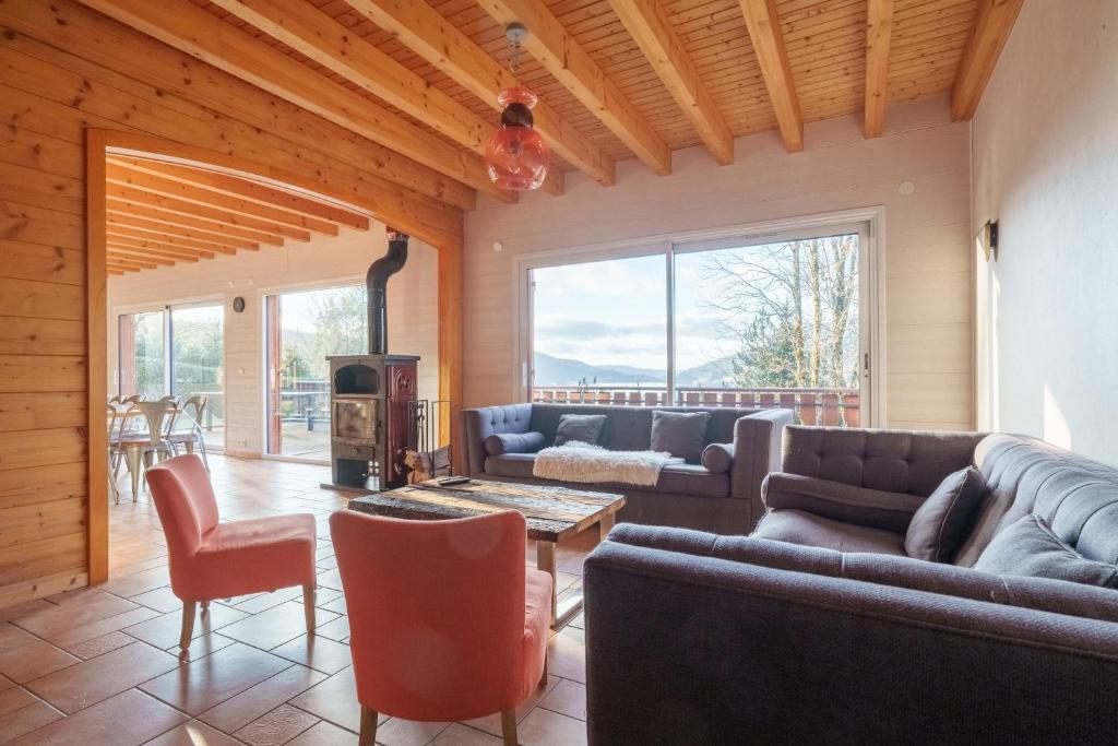 a living room with couches and a table and chairs at Chalet La Rayée - Vue lac et montagne 14p in Gérardmer