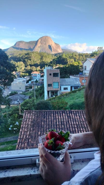 a woman looking out a window with a plate of food at Casa Vista da Pedra in Domingos Martins