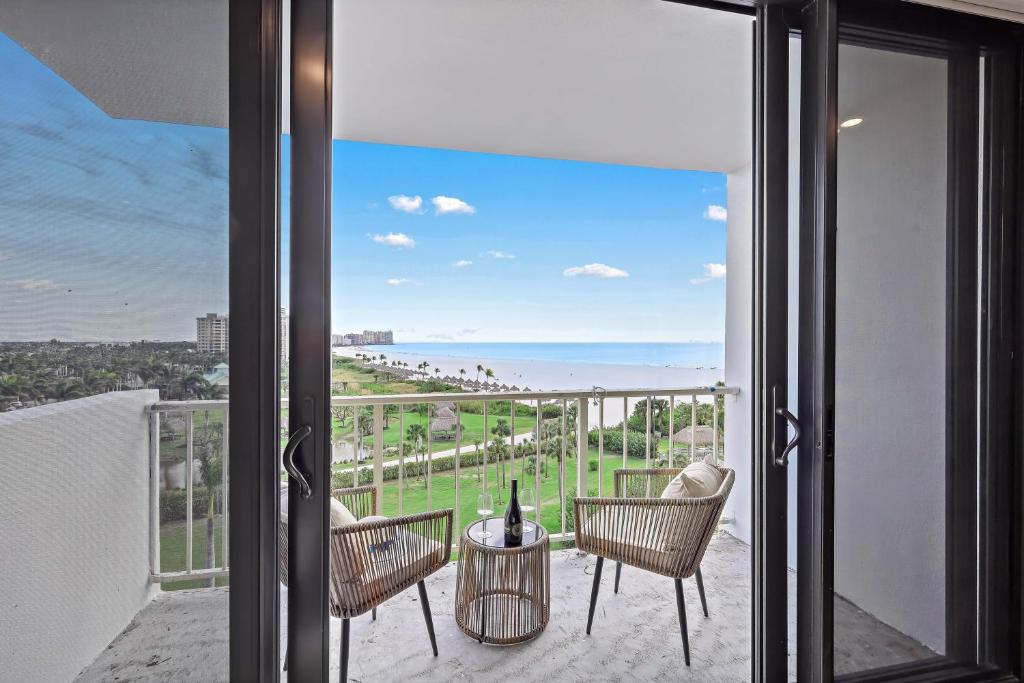 a balcony with chairs and a view of the beach at Beachfront condo with views of beach and spacious pool in Marco Island