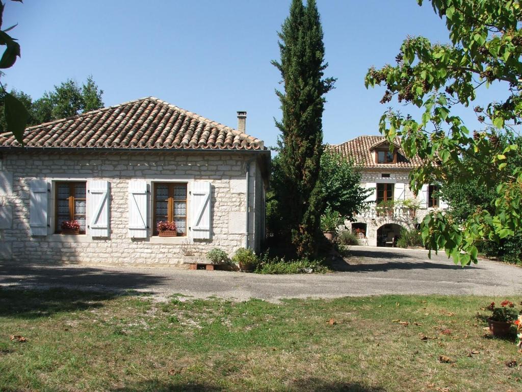 une maison en pierre avec un arbre devant dans l'établissement Gite le sabatou - la grange de cezac, à Cézac