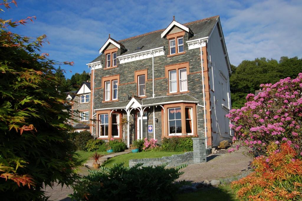 una vieja casa de ladrillo con flores delante en Maple Bank Country Guest House, en Keswick