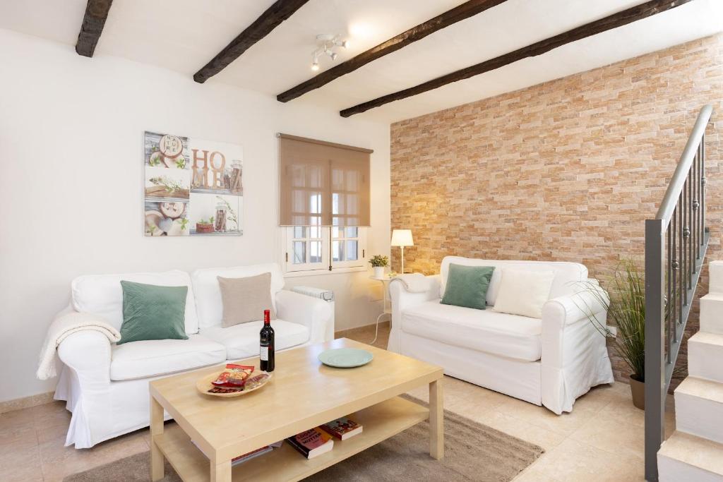 a living room with white furniture and a brick wall at Home2Book Charming Cottage Juanita Among Avocados in La Orotava
