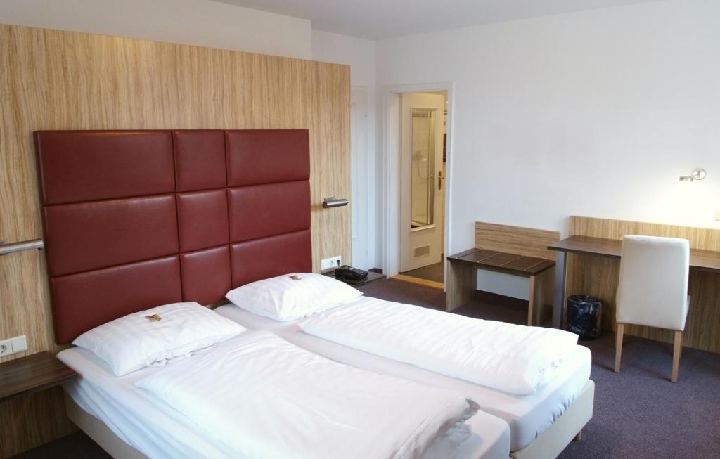 a hotel room with two beds and a desk at Hotel & Gasthaus Backmulde in Heidelberg