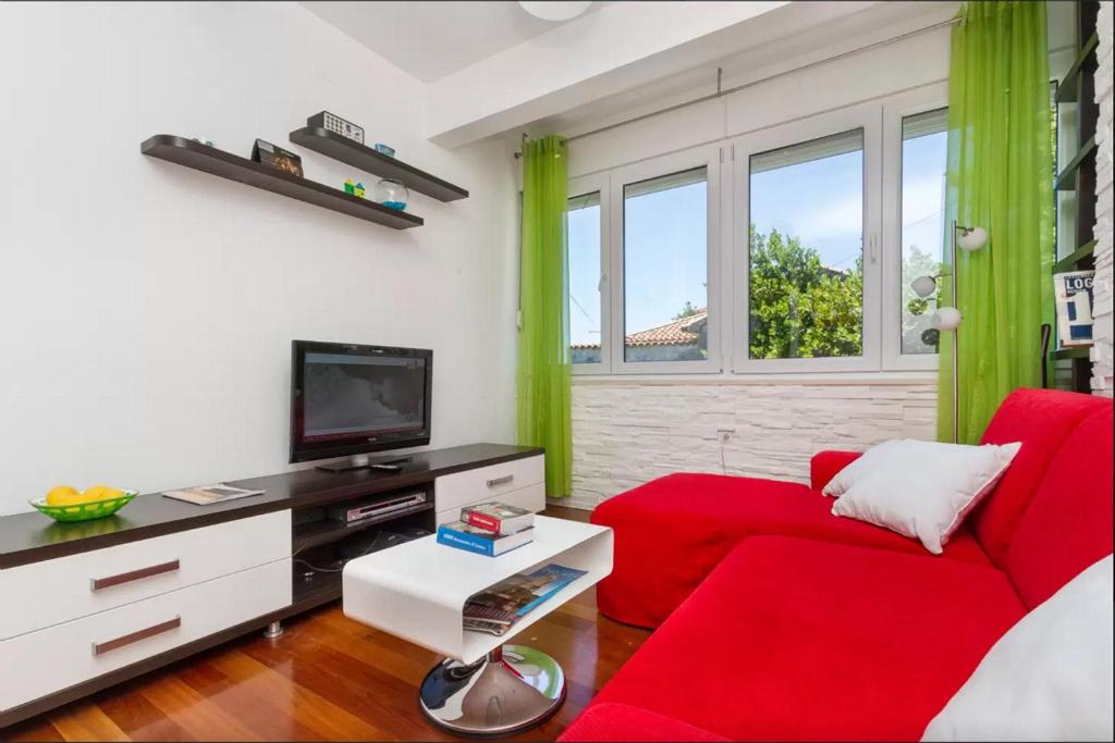 a living room with a red couch and a tv at Apartment Put Meja in Split