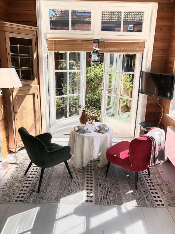 a living room with a table and chairs andwindows at t Ateliertje Noort in Bergen