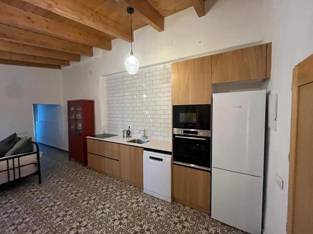 a kitchen with a white refrigerator and wooden cabinets at La Casita Soler The Soler Cottage in Arbós